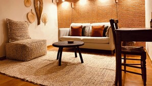 A cozy living room with a sofa, a round table, and a wooden chair. - Jas Tihou bergerie premium swimming pool Provence (Le Beausset)