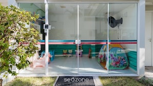 A children's play area with colorful toys and a glass entrance. - Moderno Apto c/ Piscina em Canasvieiras RCP202 (Florianópolis)
