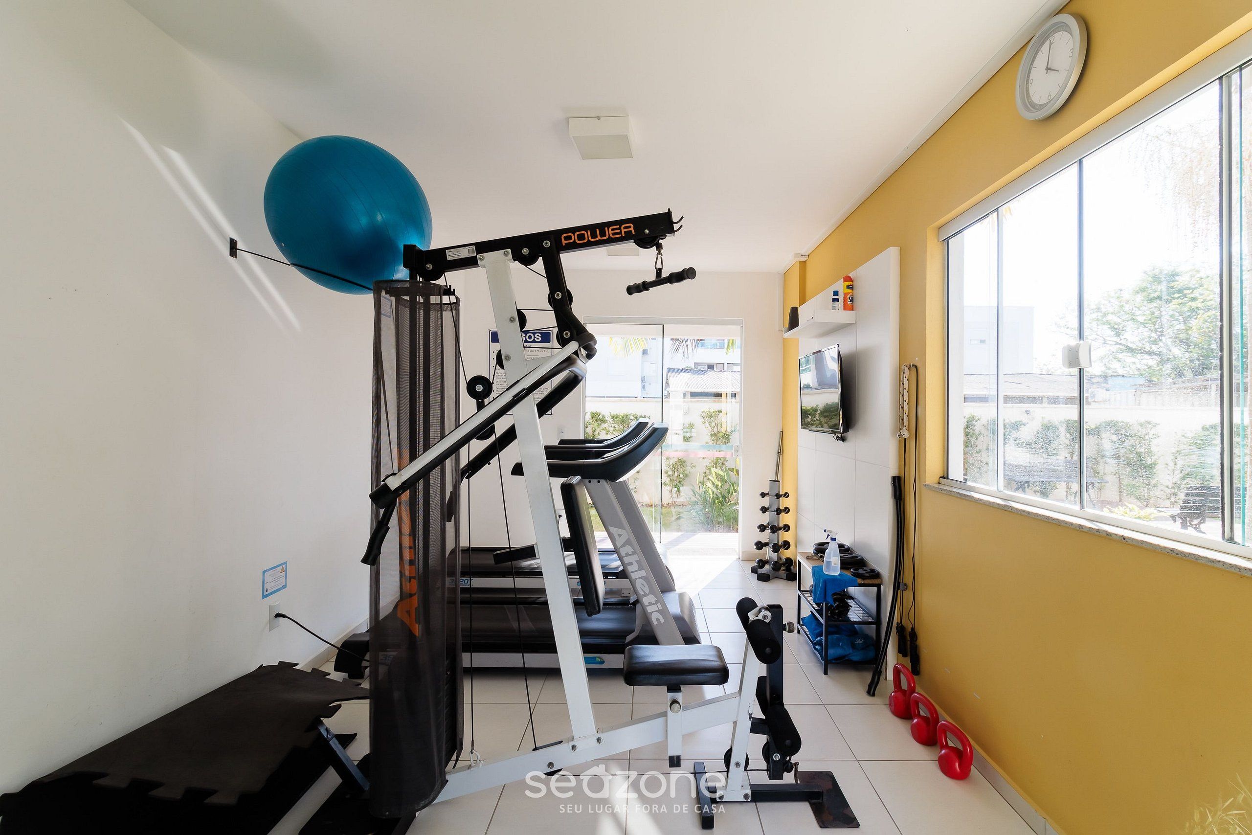 A home gym with a treadmill, weight bench, and exercise balls.