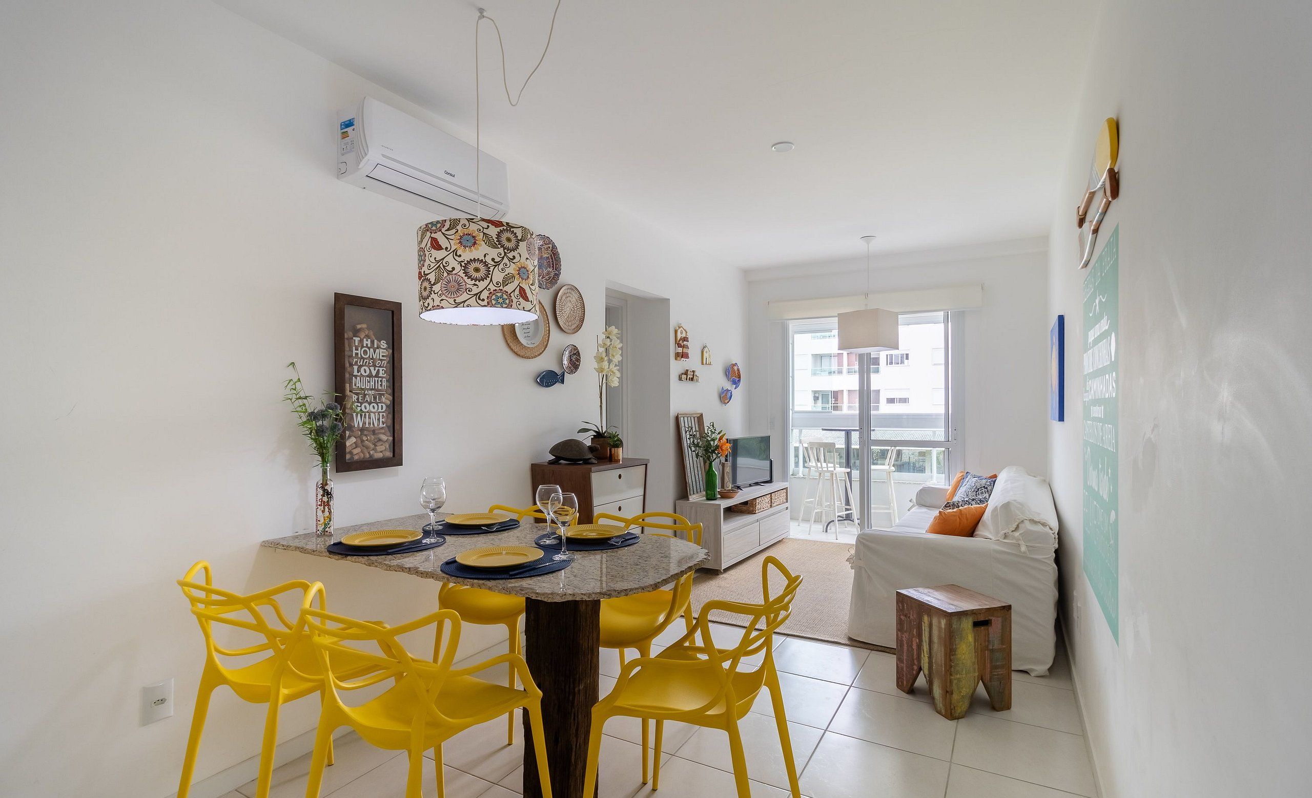 A modern dining area with yellow chairs, a round table, and a decorative light fixture.