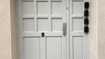 Une porte blanche à deux battants, portant le numéro « 5 » et munie d’une fente pour le courrier sur le côté droit.