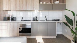 A modern kitchen with wooden cabinets, a stainless steel countertop, and a built-in oven. - Century City Escape | Walk to Shops and Views (Cape Town)