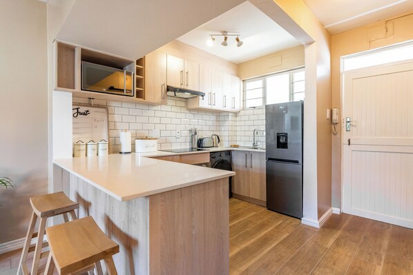 Una cocina moderna con una isla central, armarios de madera, un refrigerador de acero inoxidable y un horno empotrado.