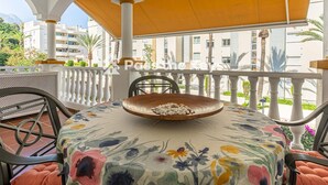 A balcony with a table, chairs, and a decorative bowl.