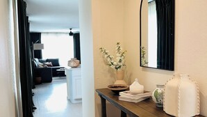 A hallway with a wooden floor, a dark wooden console table with baskets, a vase with flowers, and a mirror on the wall. - Lackland Air Force Base at 9 min-Brauning Lake at 25 min-3 bdr-King size-Grill (Von Ormy)