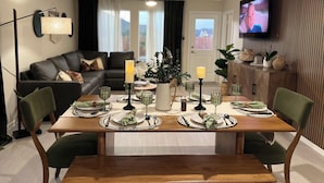 A dining area with a wooden table set for two, surrounded by green upholstered chairs. - Lackland Air Force Base at 9 min-Brauning Lake at 25 min-3 bdr-King size-Grill (Von Ormy)