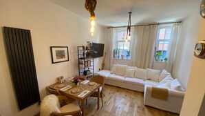 Ein gemütliches Wohnzimmer mit einer Couch, einem Esstisch für zwei Personen und einem Bücherregal.