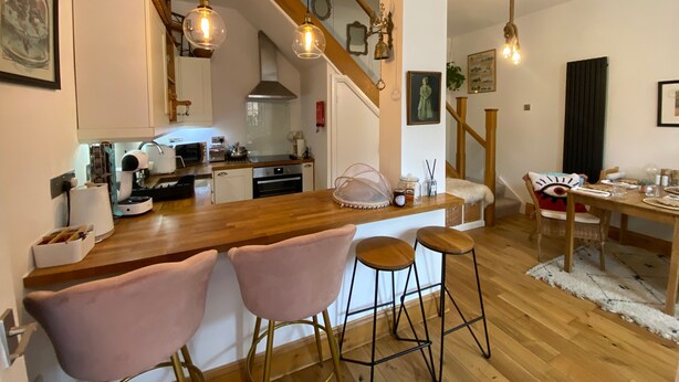 Eine moderne Küche mit Holzarbeitsplatten, einem eingebauten Backofen und einem Essbereich mit einem Holztisch und Barhocker.
