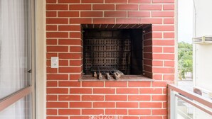 A brick wall with a built-in grill and a power outlet.