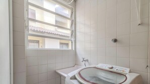 A small bathroom with a window, a washing machine, and a sink.