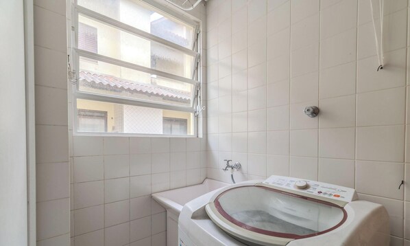 Ein kleines Badezimmer mit Fenster, einer Waschmaschine und einem Waschbecken.