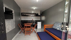 Een kleine kamer met een bed, een kitchenette en een eethoek.