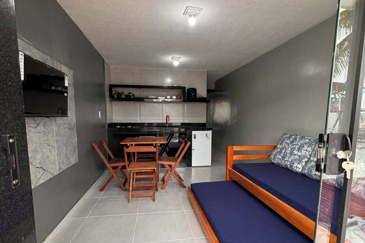 A compact room with a bed, a kitchenette, and a dining area.
