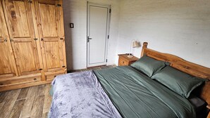 A bedroom with a wooden bed, a nightstand, a wooden wardrobe, and a door. - Brand new! Charming corner in the sierras (Marmarajá)