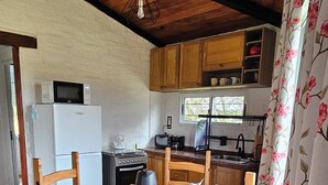 A wooden dining table with chairs, a microwave, and a kettle on the table. - Brand new! Charming corner in the sierras (Marmarajá)