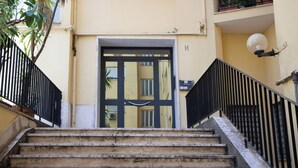 Un escalier en béton mène à une porte dotée d’un cadre noir et d’un panneau de verre.