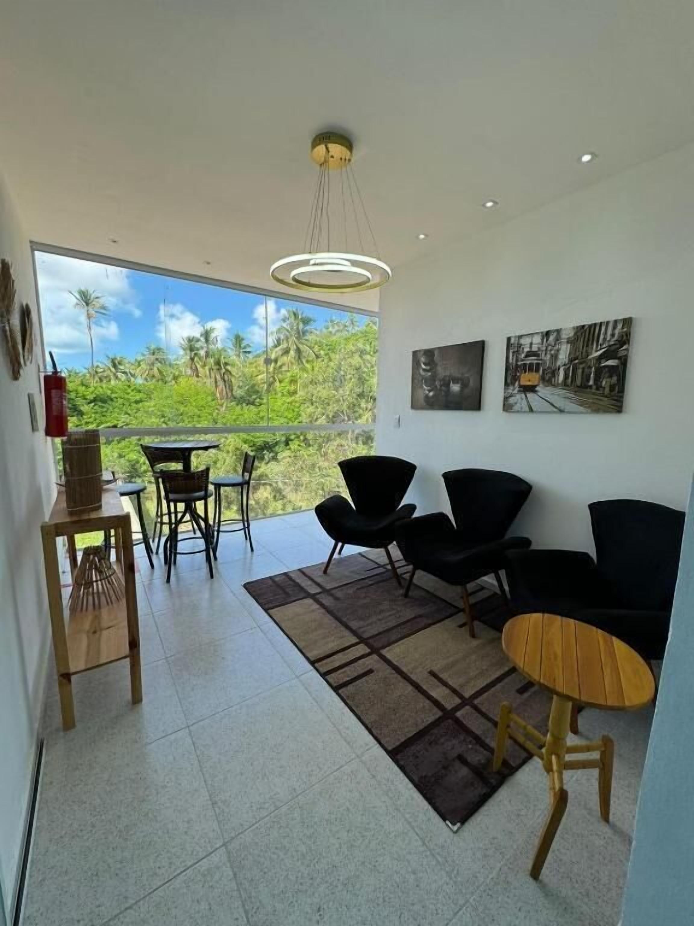 Una sala de estar moderna con balcón, muebles negros y obras de arte en la pared.