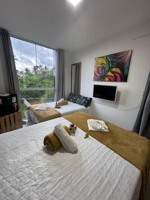 Une chambre d’hôtel avec deux lits, une télévision et un tableau au mur.