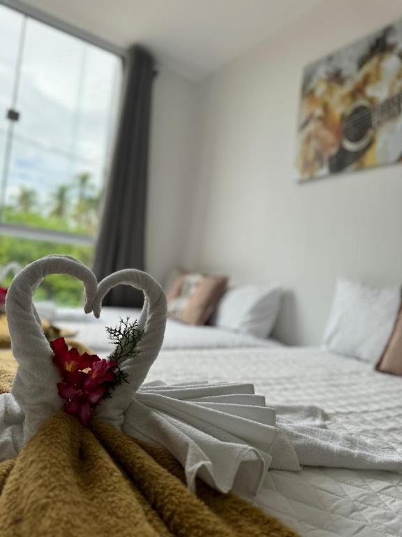 Una cama bien hecha con una decoración de toalla con forma de corazón y un ramo de flores.