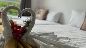 A neatly made bed with a heart-shaped towel decoration and a bouquet of flowers. - Hercules Beach Paradise (Maragogi)