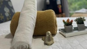 A bed with a rolled white towel, a brown towel, and two small potted plants on a tray. - Hercules Beach Paradise (Maragogi)