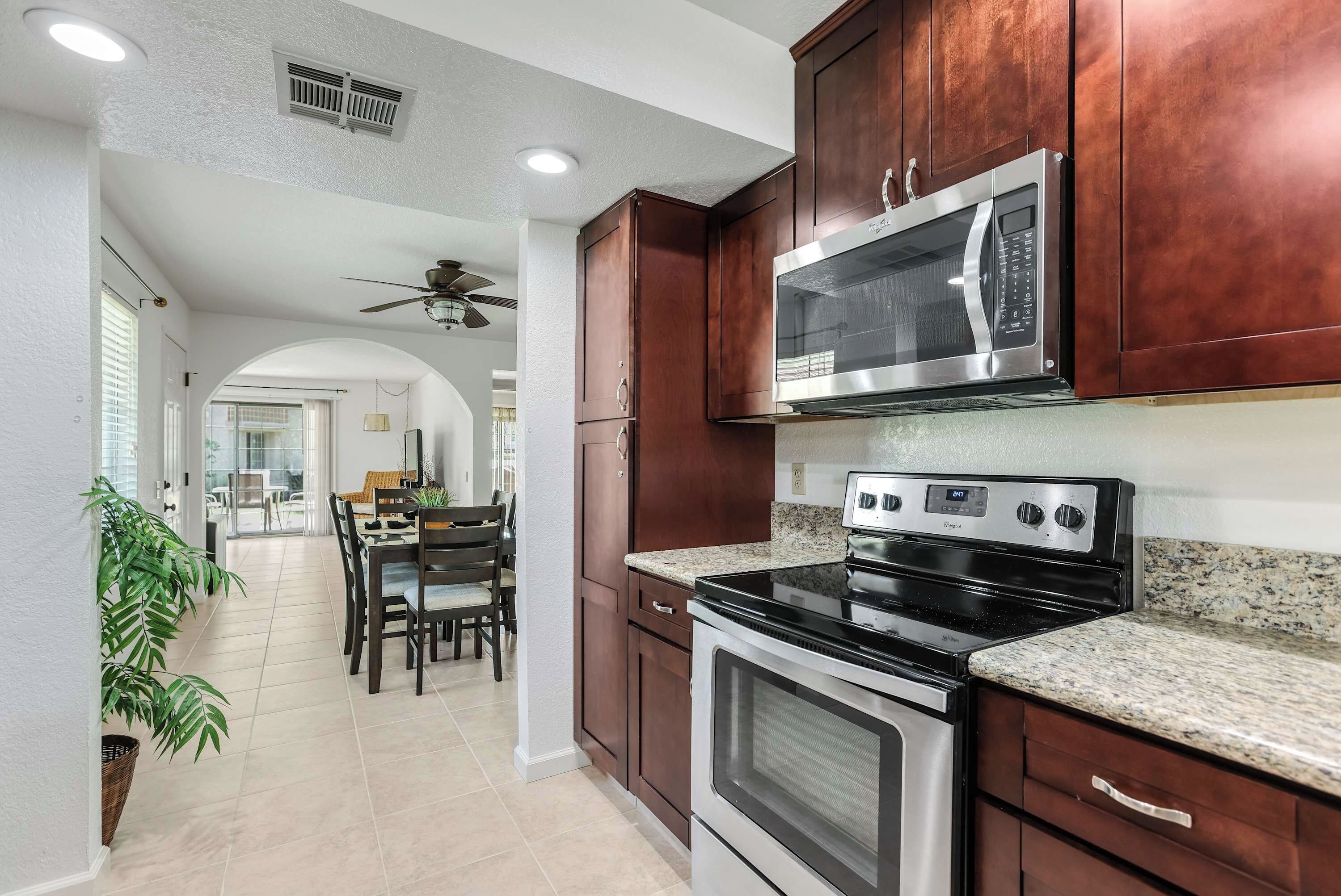 A modern kitchen with dark wood cabinets, stainless steel appliances, and a granite countertop.