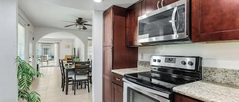 A modern kitchen with dark wood cabinets, stainless steel appliances, and a granite countertop.