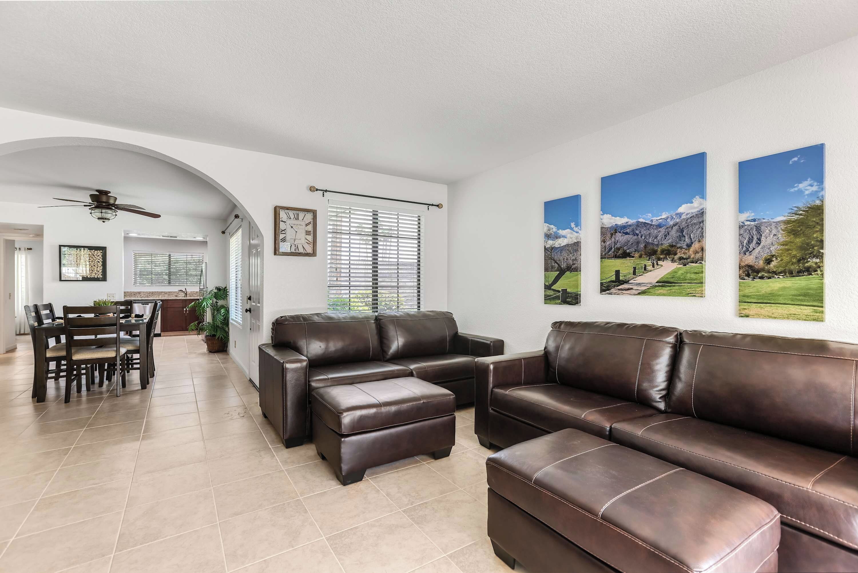 A spacious living room with a sectional sofa, a dining table with chairs, and a kitchen in the background.