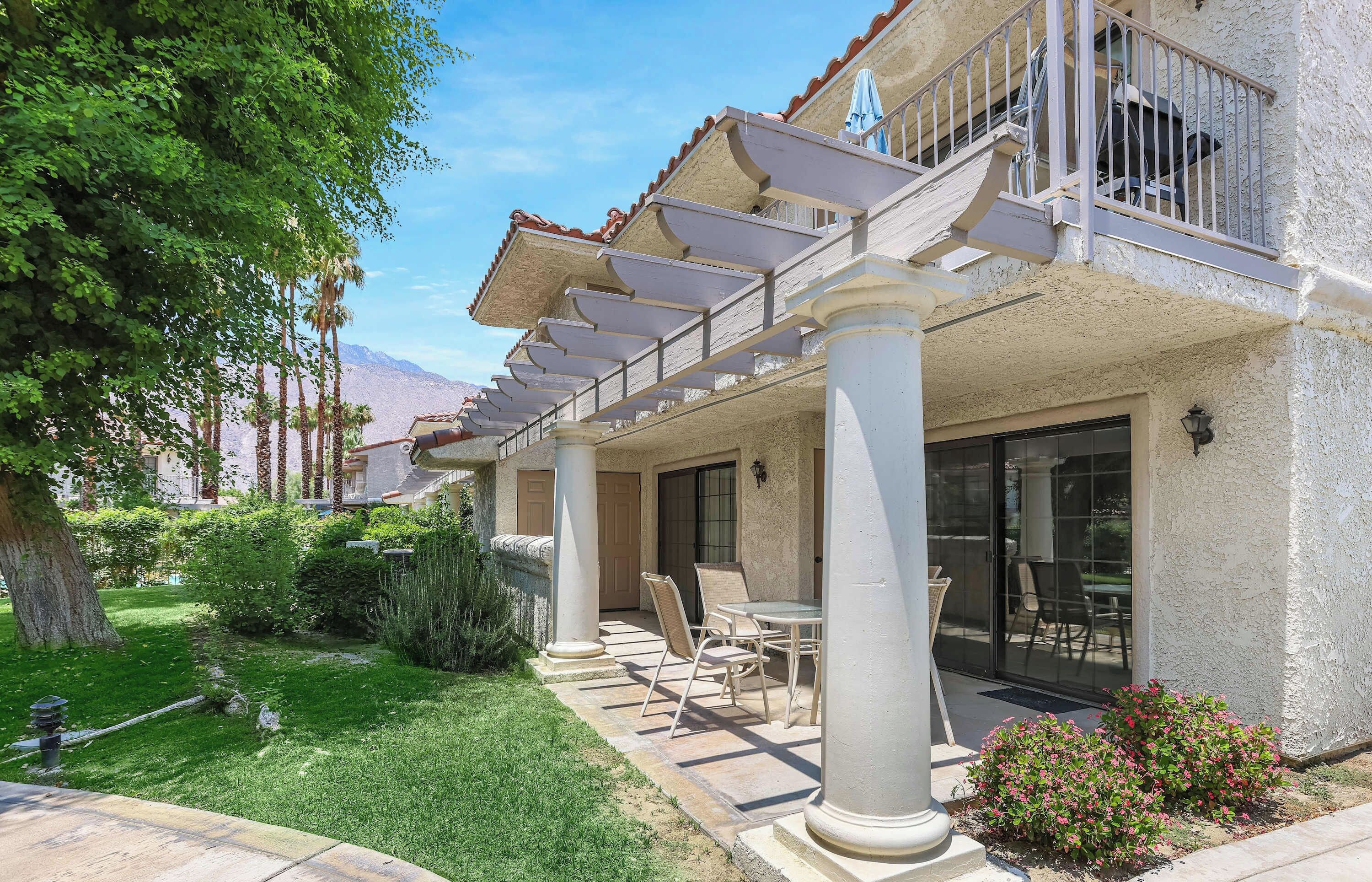 Front exterior of the condo with a shaded ground-floor patio and landscaped lawn.