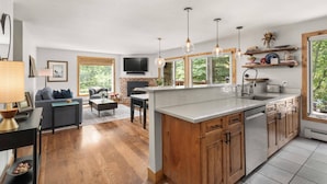 A modern kitchen with a large island, wooden cabinets, and pendant lighting. - Woodbridge 04A (Snowmass Village)