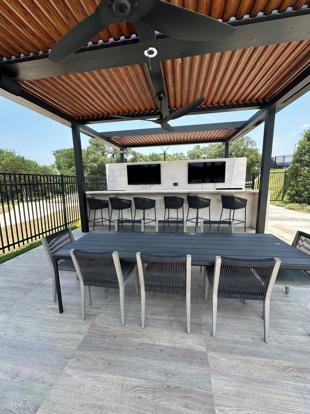 Eine Terrasse im Freien mit Grill, Sitzgelegenheiten und einem an einer Steinmauer befestigten Fernseher.