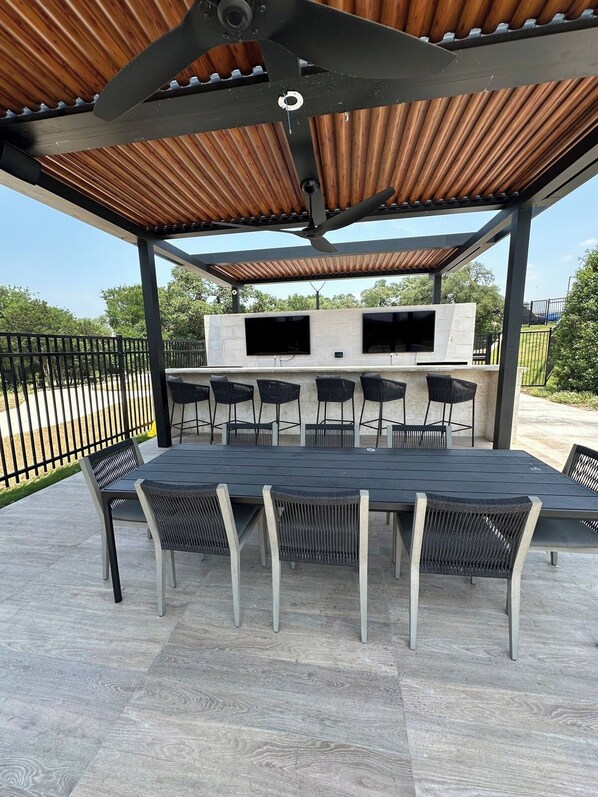 Un patio exterior con una parrilla, asientos y un televisor montado en una pared de piedra.