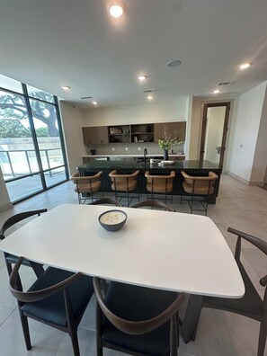 Een moderne keuken met een centraal eiland, een eettafel met vier stoelen, en een groot raam dat zorgt voor natuurlijk licht.
