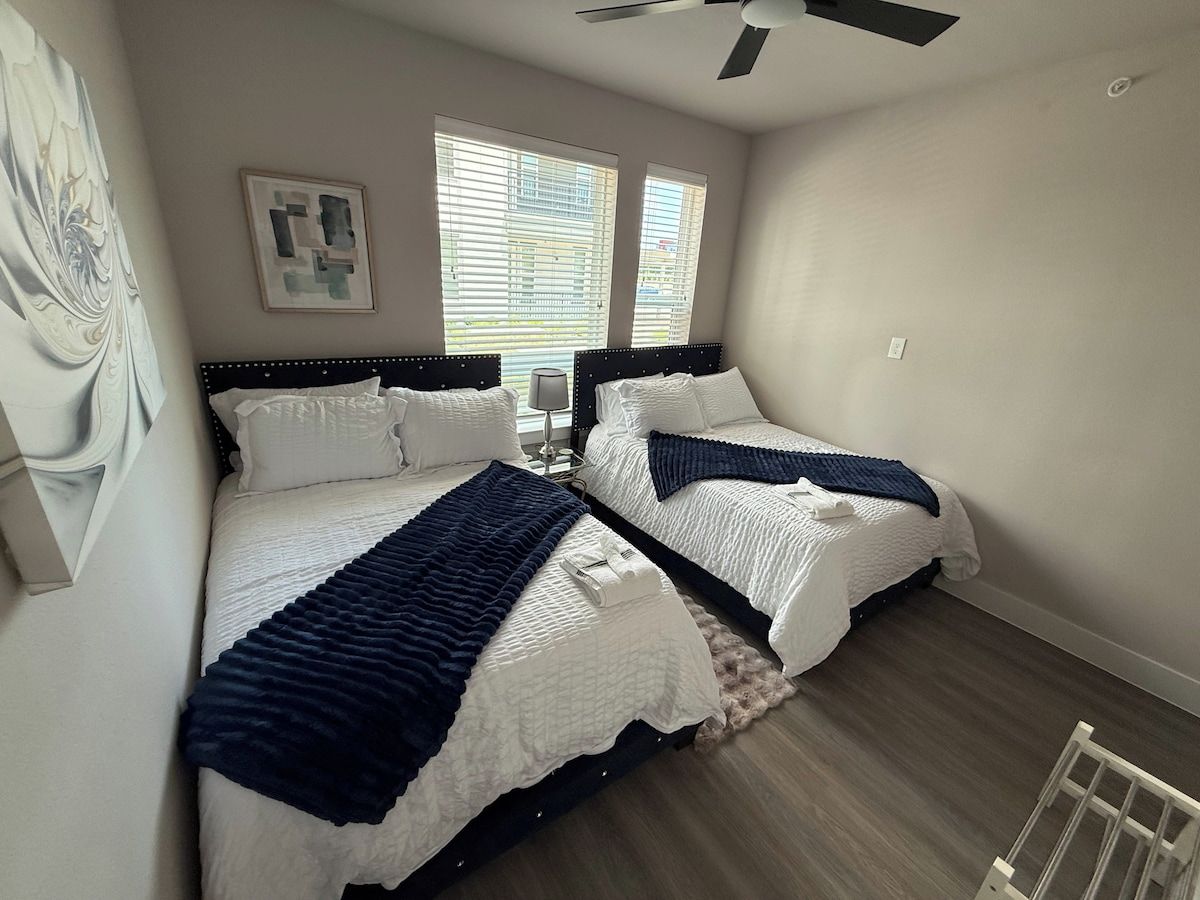 Ein Schlafzimmer mit zwei Betten, einem Deckenventilator und einem Fenster mit Jalousien.