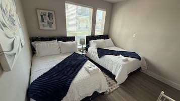 Ein Schlafzimmer mit zwei Betten, einem Deckenventilator und einem Fenster mit Jalousien.