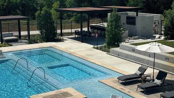 Une piscine avec des chaises longues et un espace salon abrité.