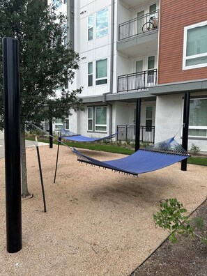 Een woongebouw met meerdere balkons, een hangmat en een boom.