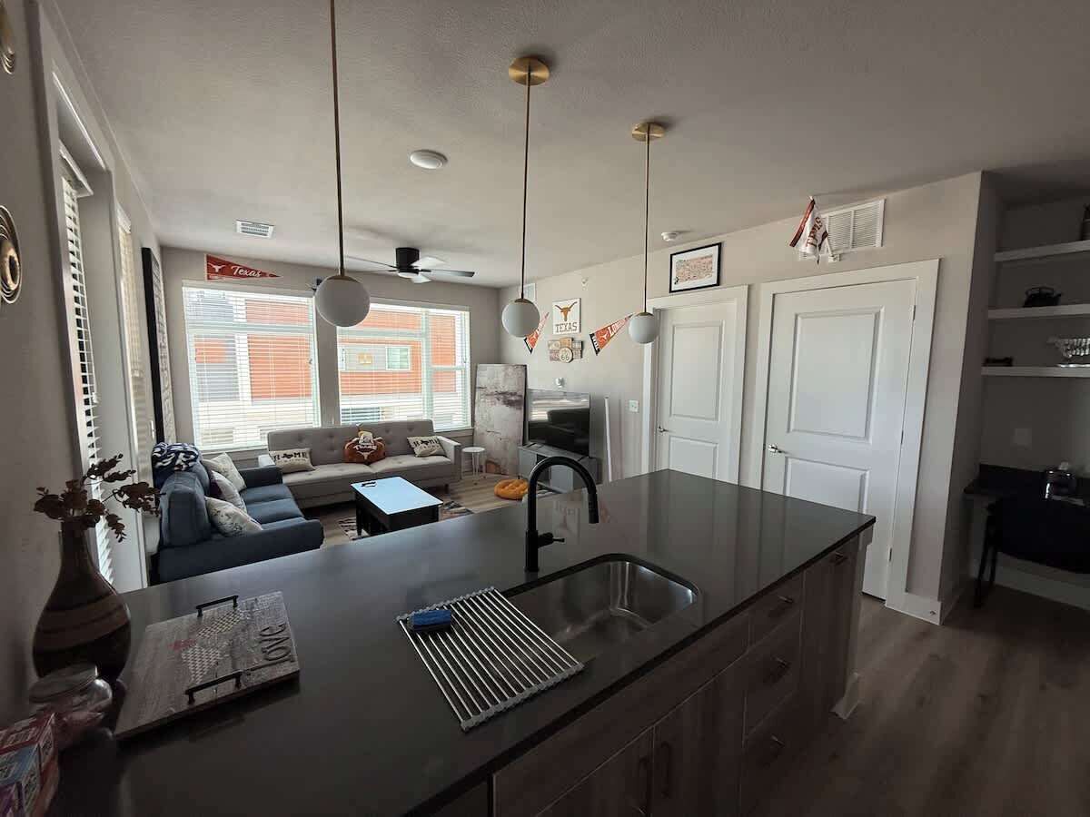 A modern kitchen with a central island, a dining area with a sofa, and a view of the outside.