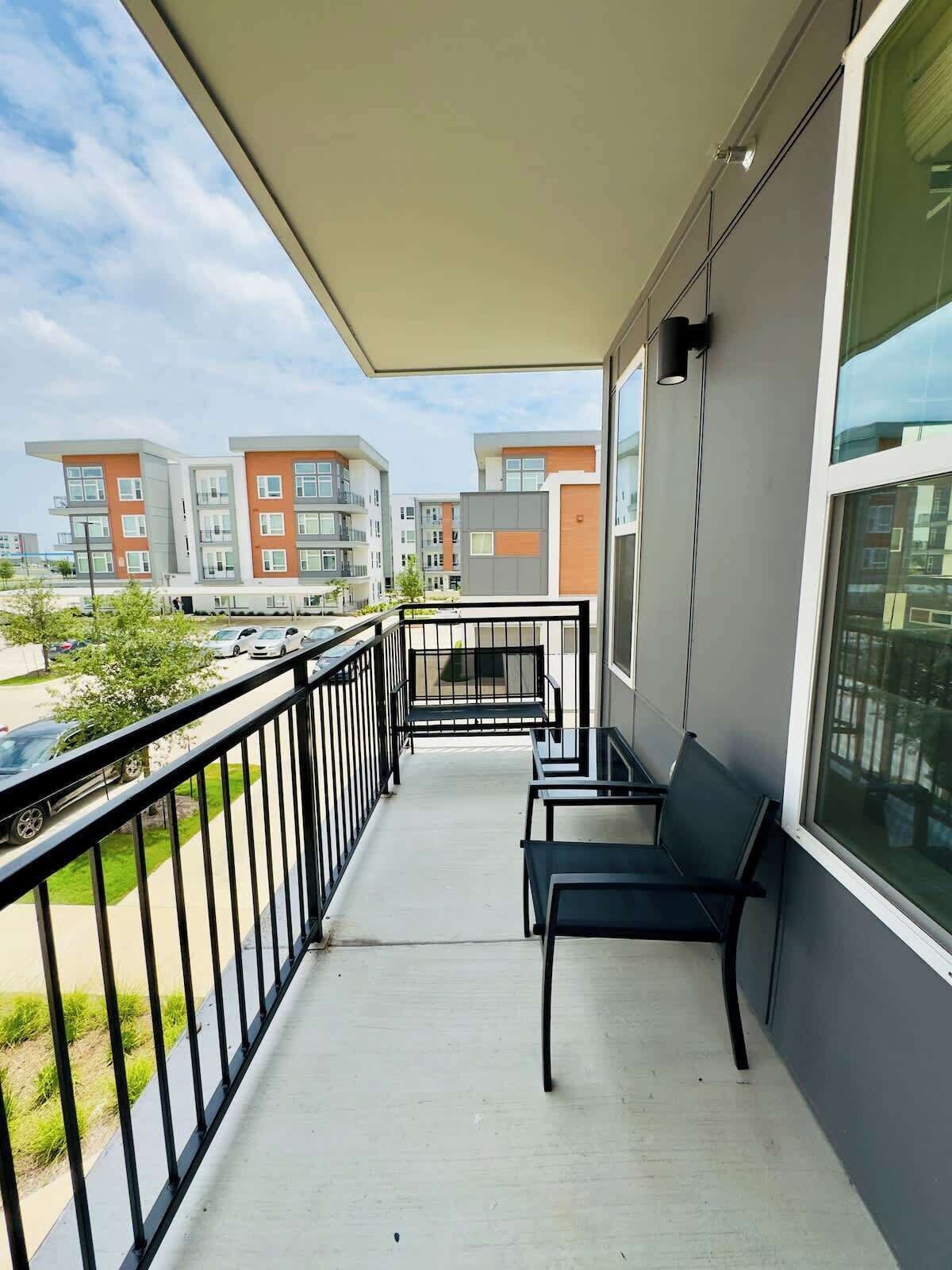 A balcony with a view of multi-story buildings, a railing, and a bench.