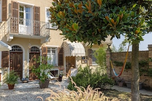 A traditional building with a balcony, potted plants, and a hammock.
