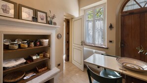 A kitchen with shelves, a dining table, a window, and a wooden door.