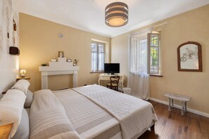 A bedroom with a bed, a desk, a chair, a television, and a small table.