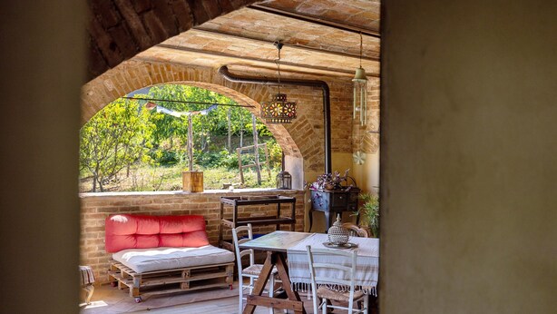 Habitació acollidora amb una banca de fusta, una taula amb cadires i una vista per una finestra apuntada.