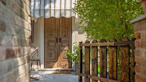 Una porta de fusta amb detalls tallats, una reixa de metall i un mur de rajola.