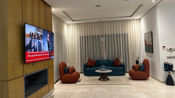 Un saló modern amb un televisor de pantalla plana, dos sofàs i una taula de centre.
