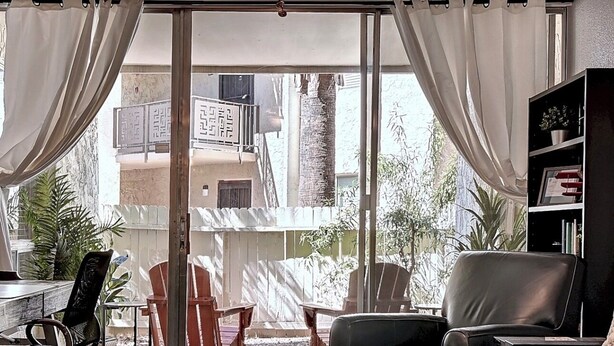Ein Wohnzimmer mit Deckenventilator, einer Couch, einem Couchtisch und einem Bücherregal.
