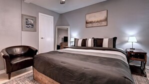 Ein Schlafzimmer mit Bett, Sessel, Deckenventilator, Nachttisch und Lampe.