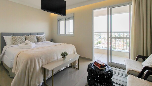 A hotel room with a bed, a TV, a window, and a balcony.