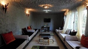Un salon chaleureux avec un mur en pierre, deux canapés, une table basse et un téléviseur fixé au mur.