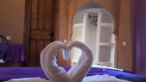 Un lit décoré avec des serviettes disposées en forme de cœur.